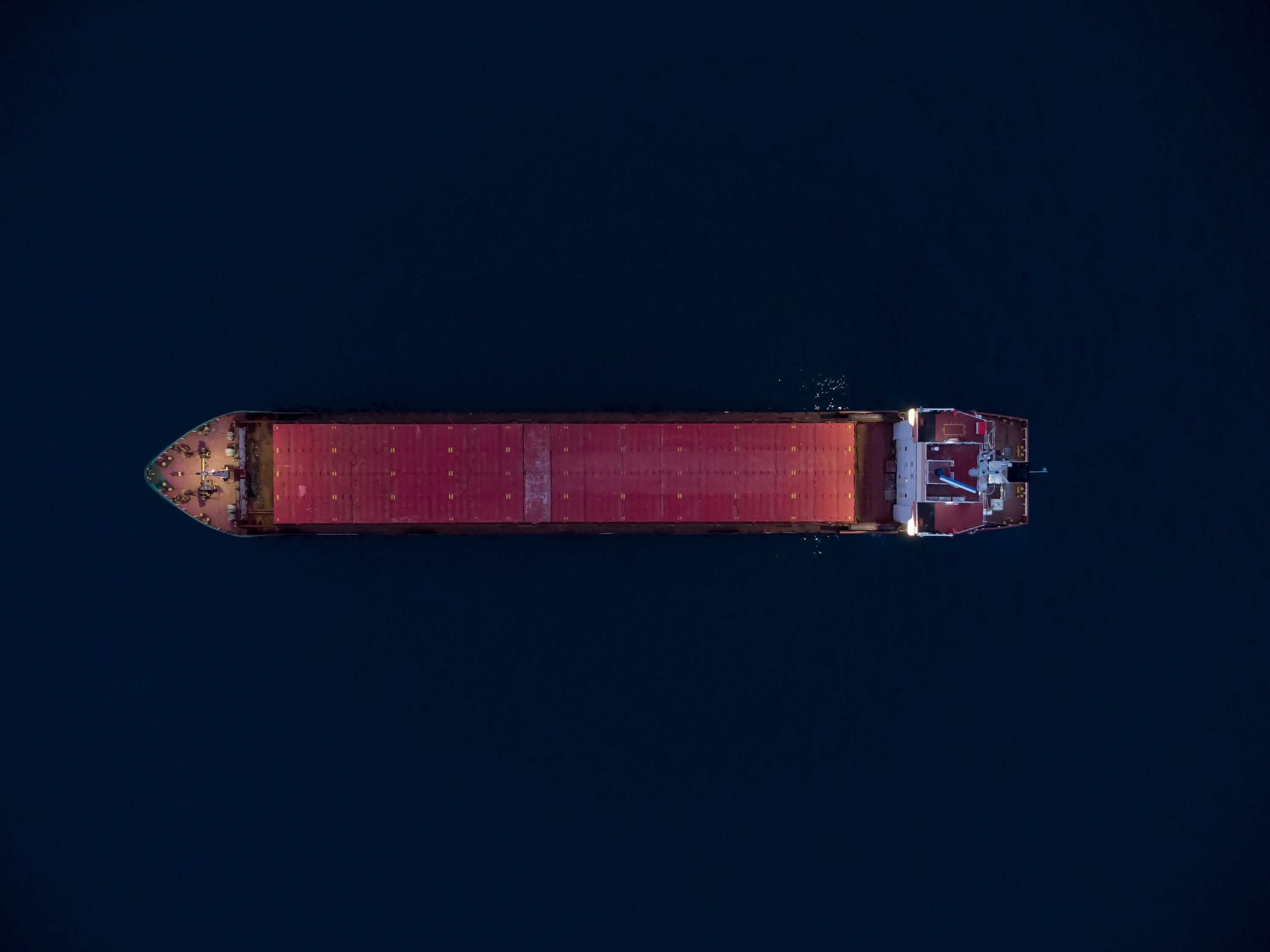 Aerial overhead view of a red bulk cargo ship at sea